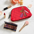 Estée Lauder red tassel makeup pouch styled with luxury makeup products - front