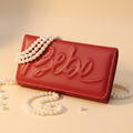 Bebe Louisa red trifold wallet elegantly surrounded by pearls - luxury flat lay