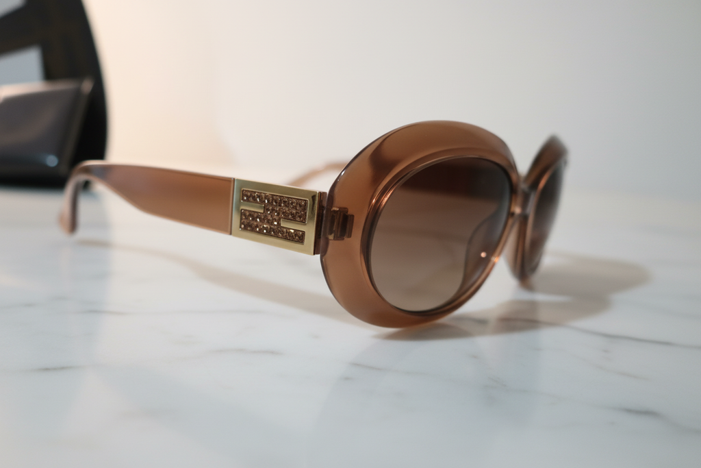 Close up of gold Fendi FF logo on brown sunglasses frame