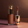 Rare Beauty Positive Light Liquid Luminizer in Tranquil on warm terracotta background with golden light